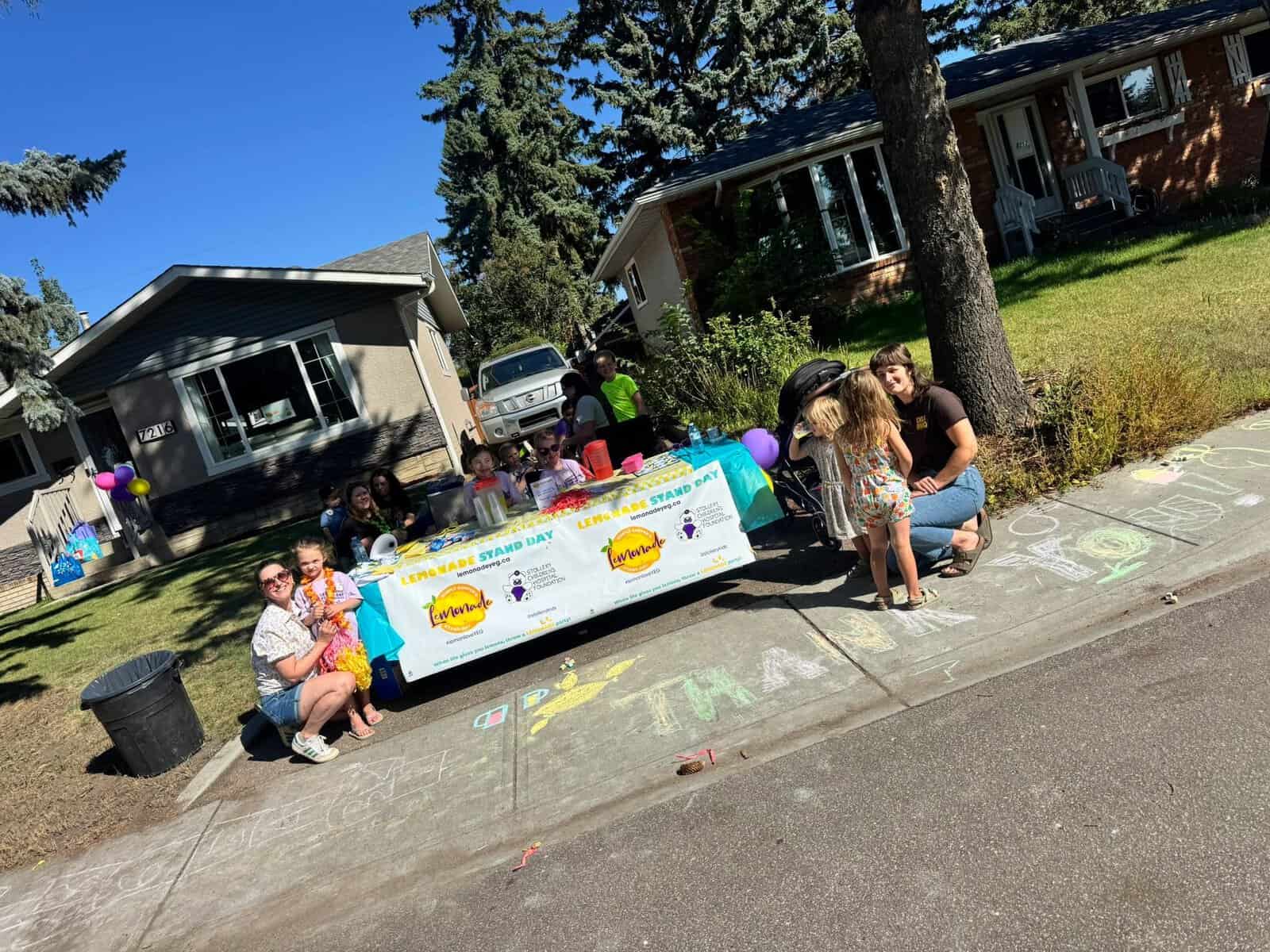 Children and families enjoying Lemonade Stand Day 2025 with colorful lemonade stands, chalk art, and outdoor activities in a residential neighborhood.